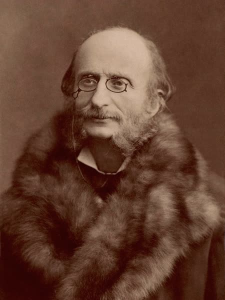 Photograph of Jacques Offenbach with pince-nez glasses and long sideburns, wrapped in a large fur coat