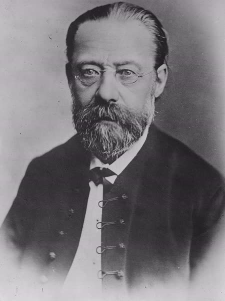 Black-and-white photograph of Bedřich Smetana with swept-back hair, small round glasses, and a greying beard