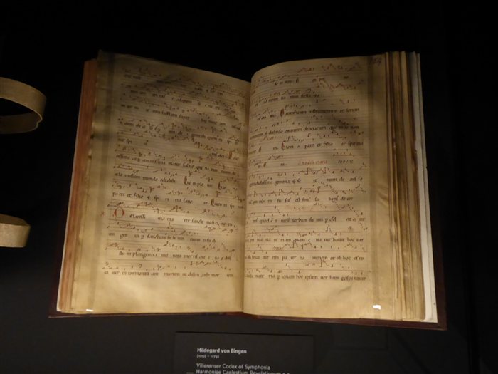 An open manuscript of Hildegard von Bingen's Symphonia Harmoniae Caelestium Revelationum on display, showing chant notation across two pages